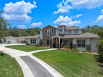Stunning exterior elevation with stone accents, a long driveway, and lush landscaping at 20199 Sweetwood Ln, Clermont, FL 34715