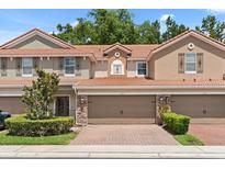 Inviting two-story townhouse features a red tile roof, two-car garage, and beautifully maintained landscaping at 299 Terracina Dr, Sanford, FL 32771
