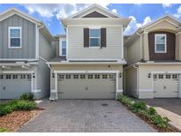 Inviting two-story home with a two-car garage and a charming brick driveway, enhancing curb appeal at 4313 Gumbo Limbo Dr, Orlando, FL 32822