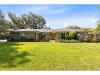Charming single-story home featuring a well-manicured lawn, stone accents, and an inviting orange front door at 5370 Whispering Pine Cir, St Cloud, FL 34771