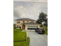 Two-story home featuring solar panels, a two-car garage, a well-manicured lawn, and a driveway with a parked car at 834 Oglethorpe Ct, Kissimmee, FL 34758