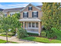 Charming two-story home featuring a cozy front porch with white railings and lush landscaping at 9189 Camden Gardens St, Orlando, FL 32827