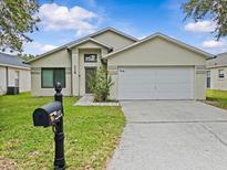 Inviting single-story home featuring a well-maintained lawn, neutral paint, and an attached two-car garage at 1112 Winding Water Way, Clermont, FL 34714