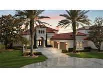 Elegant stucco home features a red tile roof, arched windows, lush landscaping and a circular driveway at 14724 Avenue Of The Rushes, Winter Garden, FL 34787