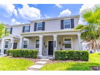 Charming two-story home featuring a covered porch, gray stucco, and lush, landscaped front yard at 15030 Book Club Rd, Winter Garden, FL 34787