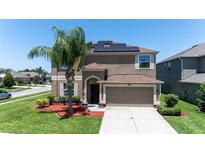 Inviting two-story home with a well-manicured lawn, solar panels, and an attached two-car garage at 1902 Hailsham Ct, Orlando, FL 32824