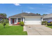 Charming single-Gathering home features a two-car garage, lush lawn, and a welcoming red front door at 204 Bay Meadow Dr, Kissimmee, FL 34746