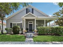 Charming gray home with a covered front porch, manicured lawn and garden and beautiful blue sky at 2215 Guiana Plum Dr, Orlando, FL 32828