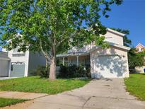 Charming two-story home with a well-manicured lawn, a front porch, and an attached two-car garage at 2320 Pebble Brook Rd, Kissimmee, FL 34741