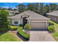 Charming single-story home with a manicured lawn, brick driveway, and two-car garage, offering curb appeal at 3677 Serena Ln, Clermont, FL 34711
