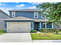 Charming two-story home featuring a two-car garage, blue siding, and well-manicured landscaping at 5967 Churchill Square Way, Groveland, FL 34736