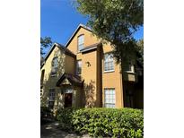 Two-story townhome with a yellow exterior, dark roof, and a well-maintained green hedge in front at 6304 Raleigh St # 204, Orlando, FL 32835