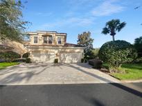 Two-story home with a two car garage and a brick paved driveway under a bright blue sky at 84 Camino Real Blvd, Howey In The Hills, FL 34737