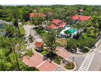 Community aerial view features red tile roofs, mature trees, community pool, and gated entrance at 935 Northern Dancer Way # 107, Casselberry, FL 32707