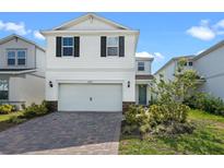 Two-story home featuring a two car garage, a teal entry door and brick paved driveway at 10245 Park Estates Ave, Orlando, FL 32836