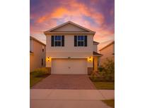 Charming two-story home with a two-car garage, brick driveway, and beautiful sunset sky at 10245 Park Estates Ave, Orlando, FL 32836
