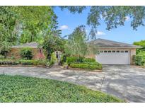 Charming single-story brick home with a well-manicured lawn, decorative gate and mature trees at 1441 Sunnyside Dr, Maitland, FL 32751