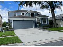 Charming two-story home featuring a two-car garage, gray facade, and manicured landscaping at 14936 Masthead Landing Cir, Winter Garden, FL 34787