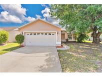 Charming single-story home with a two-car garage, well-maintained lawn, and mature shade tree at 1614 Christa Ct, St Cloud, FL 34772