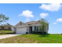 Charming single-story home with a manicured lawn, attached garage, and neutral-tone siding under a sunny sky at 2135 E Old Mill Dr, Deltona, FL 32725