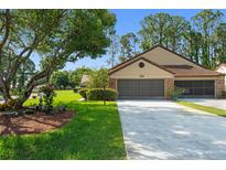 Charming home featuring a well-maintained lawn, mature trees, and an attached two-car garage at 216 Bermuda Petrel Ct, Daytona Beach, FL 32119