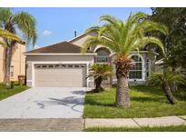 Charming single-Gathering home with a two-car garage, manicured lawn, and mature palm trees at 2506 Aster Cove Ln, Kissimmee, FL 34758