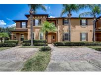 Inviting townhome featuring a brick driveway and beautiful landscaping, including mature palm trees for a tropical feel at 528 Terra Lago St, Davenport, FL 33897