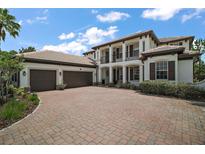 Elegant two-story home with a tile roof, brick driveway, manicured landscaping, and a three-car garage at 5683 Bassett Pl, Sanford, FL 32771
