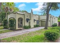 Charming single-story home with stucco exterior, arched entry, chimney, and a brick driveway leading to an attached garage at 1012 W New Hampshire St, Orlando, FL 32804