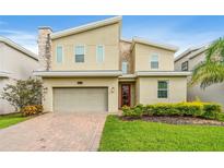 Contemporary two-story home boasts stone accents, a two-car garage, and a well-manicured lawn at 8833 Cruden Bay Ct, Davenport, FL 33896