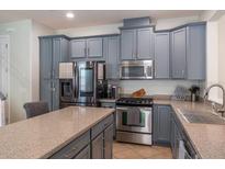 Stylish kitchen with stainless steel appliances and gray cabinets, complete with an island and granite countertops at 9575 Silver Buttonwood St, Orlando, FL 32832