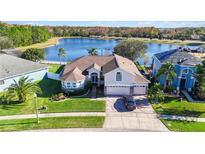 Beautiful lakefront home with lush lawn, brick driveway, and attached two-car garage at 10642 Cloudview Dr, Orlando, FL 32825