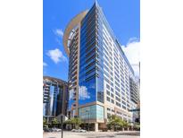Modern, high rise condominium featuring a curved facade with glass windows and balconies on a sunny day at 155 S Court Ave # 2008, Orlando, FL 32801