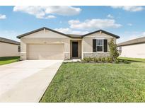 Charming single-story home boasts a well-manicured lawn and inviting neutral exterior with stone accents at 1737 Forest Run Ln, Auburndale, FL 33823