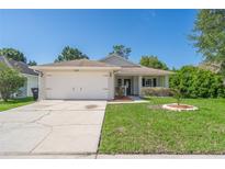 Charming single-story home with a well-maintained lawn and a two car garage and a clear blue sky at 2028 Donegan Pl, Orlando, FL 32826