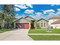 Charming home featuring a well-maintained lawn, red garage door, and lush landscaping at 321 Thomasdale Ave, Haines City, FL 33844