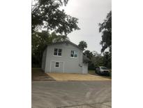 Two-story grey home featuring a gravel driveway and well-maintained landscaping, all nestled under mature trees at 647 Madison Ave, Daytona Beach, FL 32114
