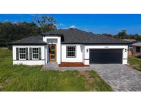 Charming single-Gathering home boasts a modern design with a brick-paved driveway and a black two-car garage at 16367 Sw 17Th Terrace Rd, Ocala, FL 34473