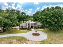Stunning brick home featuring a circular drive, mature trees, and a beautifully landscaped yard at 17524 Seidner Rd, Winter Garden, FL 34787