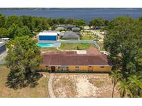 Aerial view of a yellow home with pool and partial lake view with green trees at 181 W Minnehaha Ave, Clermont, FL 34711