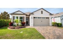 Charming single-story home featuring a manicured lawn, stone-paved driveway, and an attached two-car garage at 2156 Antilles Club Dr, Kissimmee, FL 34747