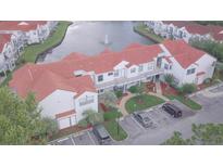 Overhead shot showcasing a condo with red tile roof, parking, and a scenic waterfront view with a fountain at 2536 Woodgate Blvd # 202, Orlando, FL 32822
