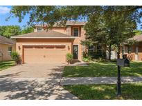 Charming two-story home featuring a manicured lawn, brick driveway, and a two-car garage at 2762 Pepper Ln, Orlando, FL 32812