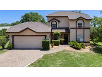 Charming two-story home with a tile roof, brick driveway, and lush green lawn at 4019 Lake Mirage Blvd, Orlando, FL 32817