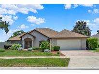 Charming single-story home with lush landscaping, a brick driveway, and an attached two-car garage at 4571 Abaco Dr, Tavares, FL 32778