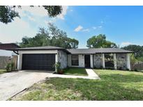 Charming home boasts a new roof, dark garage door, rock facade and freshly landscaped yard at 5805 Hutton Dr, Orlando, FL 32808