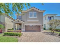 Two-story home showcasing a well-manicured front yard and a brick paved driveway leading to an attached garage at 640 Lasso Dr, Kissimmee, FL 34747