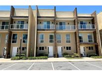 Modern townhome exterior with a glass balcony, lush landscaping and convenient parking spaces at 7667 Recife Dr, Kissimmee, FL 34747