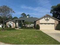 Charming single-Gathering home featuring a two-car garage, manicured lawn, and mature trees at 802 Kaywood Dr, Orlando, FL 32825