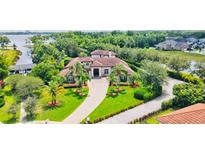 Stunning waterfront estate featuring lush landscaping, tile roof, and a grand driveway at 10352 Burris Ct, Orlando, FL 32836